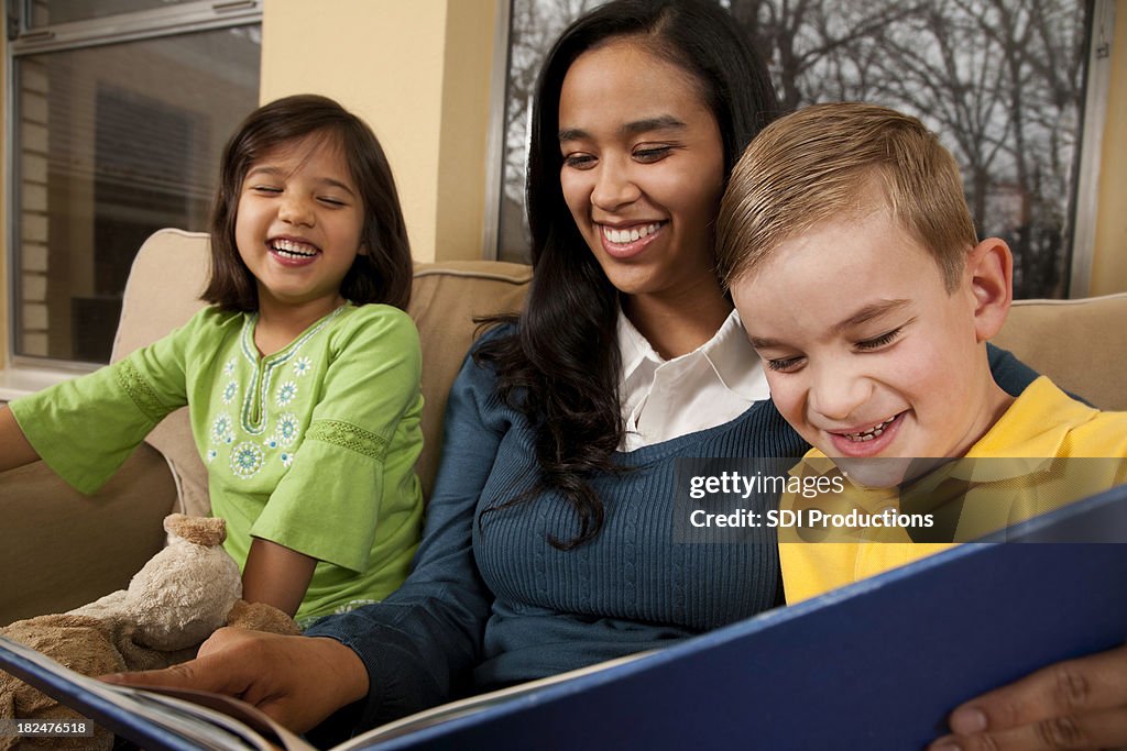 Bebê Sitter leitura com duas crianças Rir