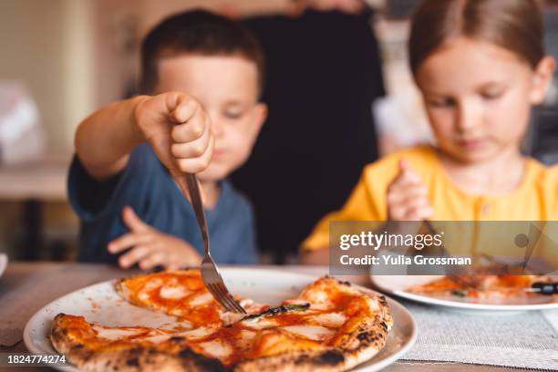 a boy and a girl share a pizza in a cafe. - pizza restaurant stock pictures, royalty-free photos & images