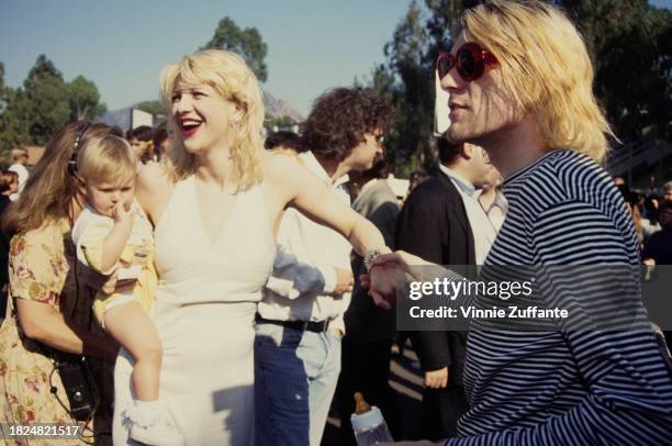 American singer, songwriter, musician and actress Courtney Love, holding her daughter Frances Bean Cobain, and her husband, American singer,...