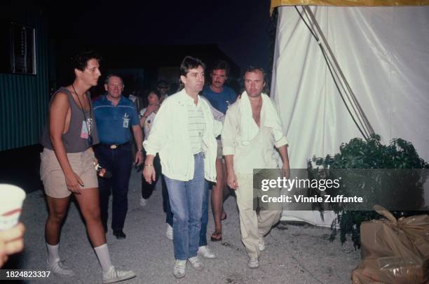 British singer, songwriter, drummer and actor Phil Collins, wearing a white shirt with white trousers, backstage at the Live Aid benefit concert,...