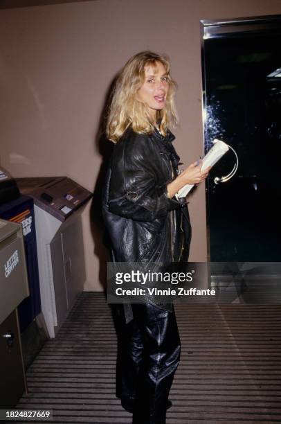 British actress Maryam d'Abo wearing a black leather jacket and black leather trousers, a document held in her hands, United States, circa 1992.