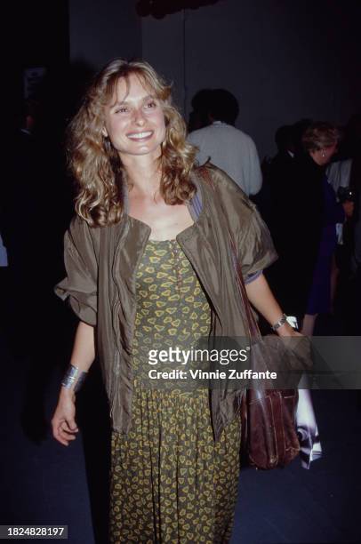 British actress Maryam d'Abo, wearing a brown jacket over an olive green-and-yellow dress, a leather shoulder bag over her left shoulder, attends the...