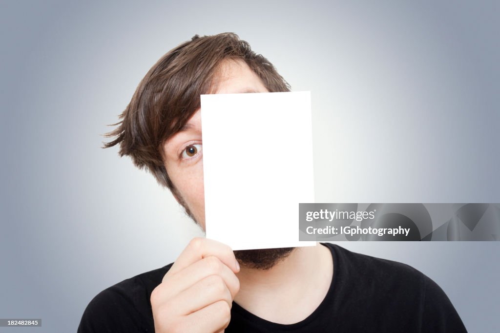 Young Man Peeping from behind a Piece of Paper