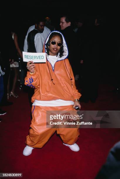 American rapper Da Brat, wearing an orange hoodie with baggy orange bottoms, holds a 'Reserved' sign as she attends the Hollywood premiere of 'A Thin...