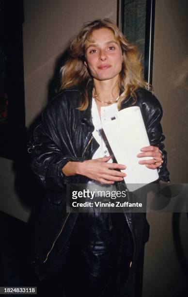 British actress Maryam d'Abo wearing a black leather jacket over a white shirt, a document held in her hands, United States, circa 1992.