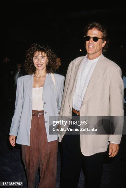 American actress Mary Steenburgen, wearing a light blue jacket and brown trousers, holding hands with American actor Ted Danson, who wears a beige...