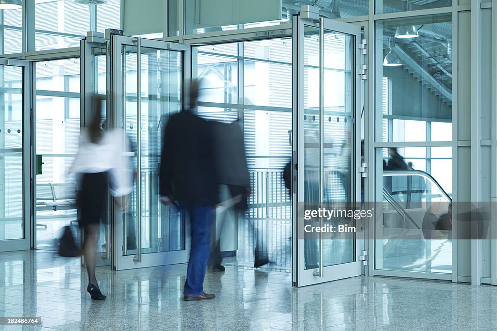 Pessoas a caminhar através da porta de entrada do edifício moderno, Movimento Desfocado