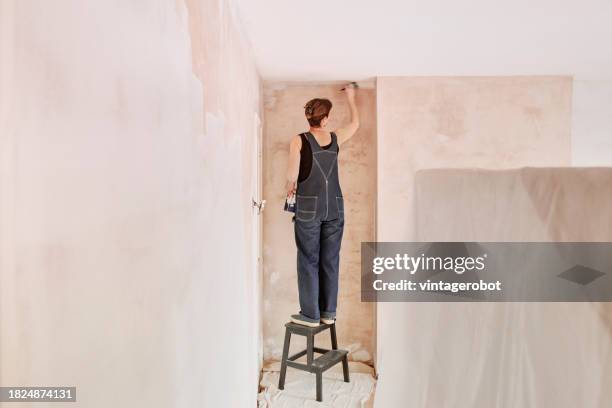 woman painting newly plastered wall - protective sheet stock pictures, royalty-free photos & images