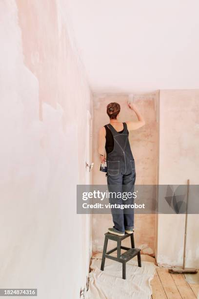 woman painting newly plastered wall - protective sheet stock pictures, royalty-free photos & images