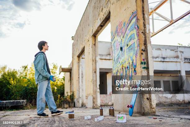 young man creating graffiti on the wall - street artist stock pictures, royalty-free photos & images