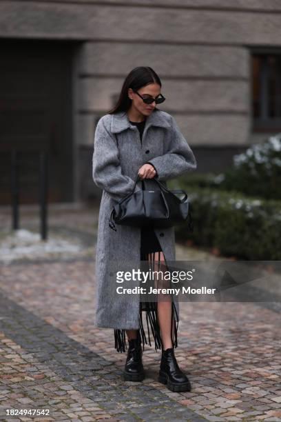 Anna Winter seen wearing Celine black sunglasses, Ganni black fringed short dress, Ganni light grey wool long coat, Loewe black leather handbag and...