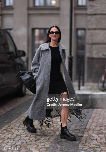 Anna Winter seen wearing Celine black sunglasses, Ganni black fringed short dress, Ganni light grey wool long coat, Loewe black leather handbag and...