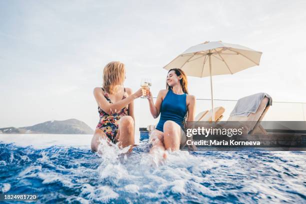 girlfriends splash, laugh and have fun in the pool. - fiesta de piscina fotografías e imágenes de stock
