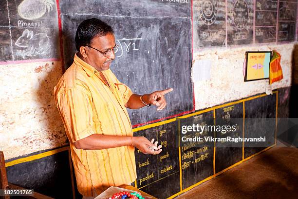 male indian teacher standing beside a blackboard - education india stock pictures, royalty-free photos & images