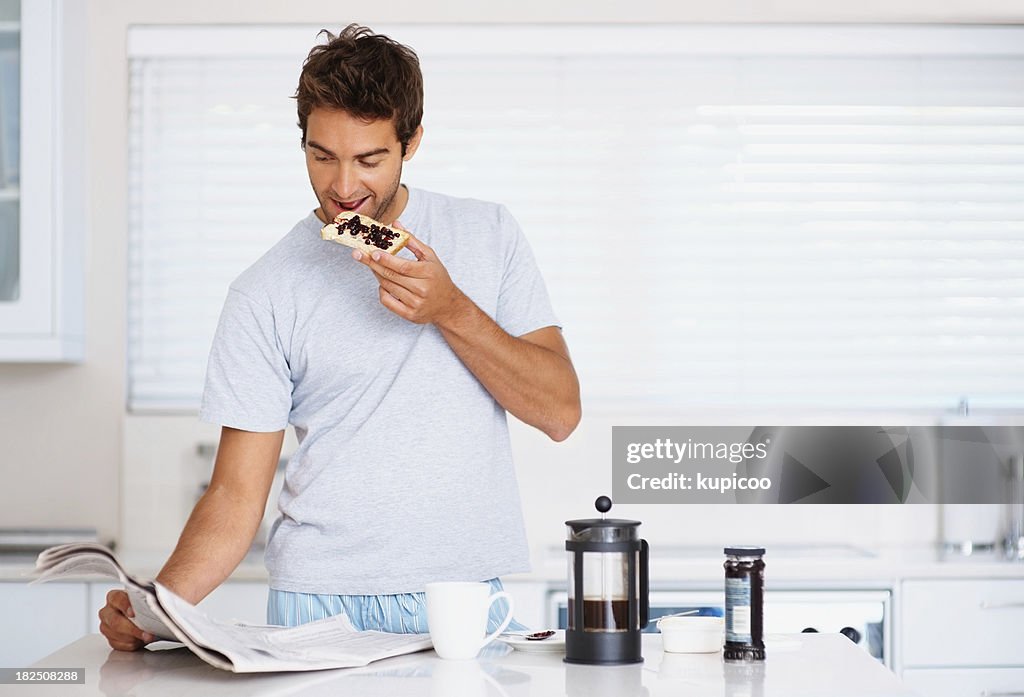 Junger Mann mit einem Frühstück white lesen Zeitung