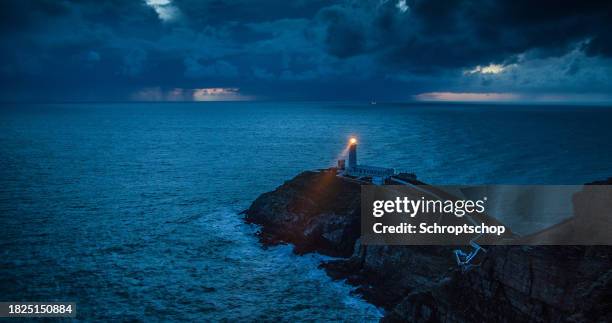 phare avec le faisceau léger au littoral orageux - phare photos et images de collection