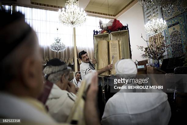 Iranian Jewish men read from the Torah scroll during morning prayers at Youssef Abad synagogue in Tehran on September 30, 2013. Present for more than...