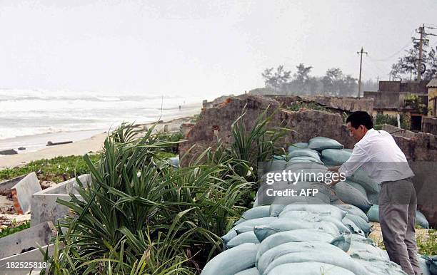 This picture taken on September 29, 2013 shows a man checking a sandbag barrier along a coastal area in Thuan An, in Vietnam's central province of...