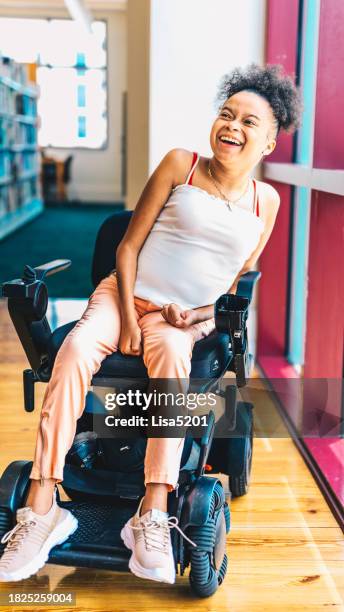 indoor portrait of a young joyful african american woman with disabilities in a motorized wheelchair - motorized wheelchair stock pictures, royalty-free photos & images