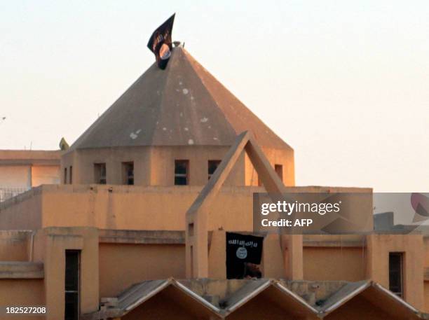 The flag of the Islamic State of Iraq and the Levant flutters on the "dome" of the Armenian Catholic Church of the Martyrs in the northern rebel-held...