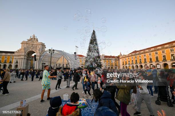 Street entertainer blows soap bubbles as a crowd gathers to watch fireworks and laser show during the lighting of a large Christmas tree and...
