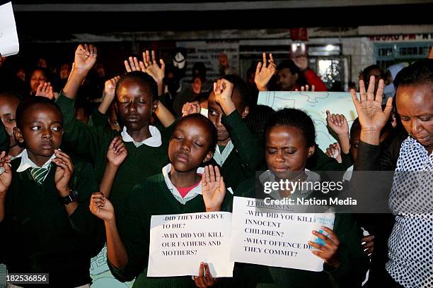 Pupils from Moi Nyeri Complex lift up their hands during prayers and tributes for the Westgate Terror attack victims on September 27, 2013 outside...