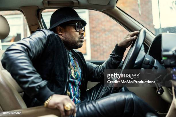 man in old school hip hop clothing driving classic car and looking out window - music from the motor city stock pictures, royalty-free photos & images