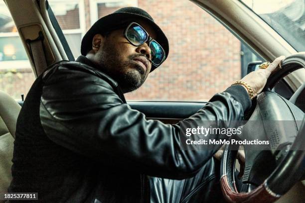 man in old school hip hop clothing driving and looking out window - music from the motor city stock pictures, royalty-free photos & images