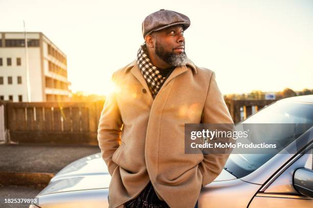 man standing of front of car at sunrise - baker boy cap stock pictures, royalty-free photos & images