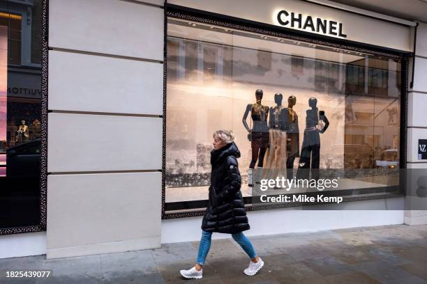 Figures of people interact with mannequins in the Chanel store window on Bond Street on 4th December 2023 in London, United Kingdom. Bond Street is...