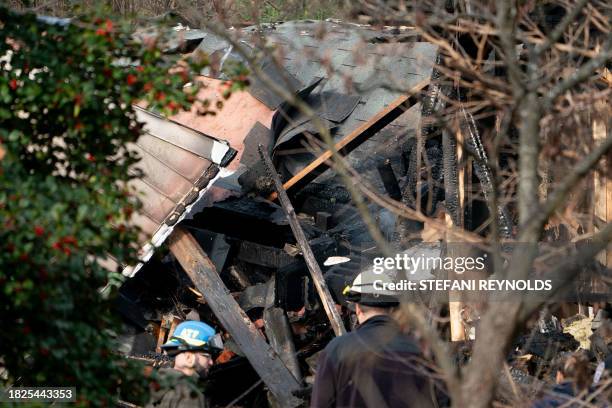 Workers look at a home that exploded in Arlington, Virginia, on December 4 and rocked a neighborhood with a powerful blast, on December 5, 2023....