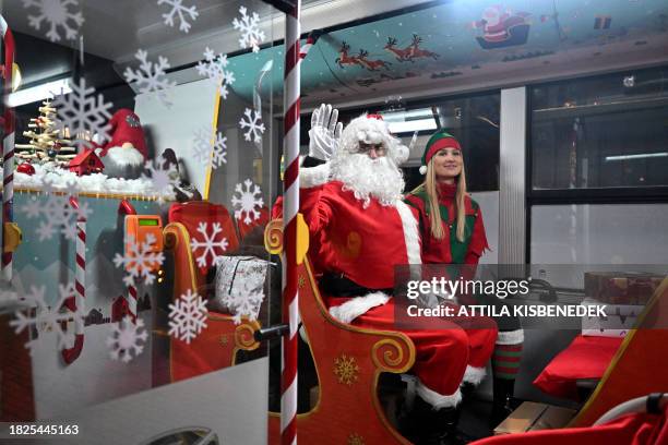 Helpers dressed as Santa Claus and Elf pose on the new so-called 'Mikulastroli' bus in Budapest on December 5 before distributing gifts in shoeboxes...