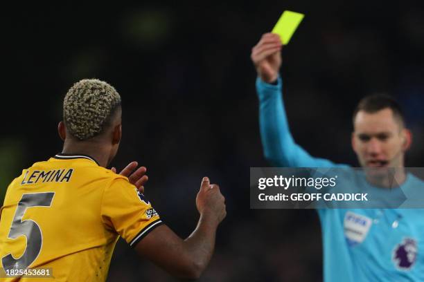 Wolverhampton Wanderers' Gabonese midfielder Mario Lemina reacts as he receives a yellow card during the English Premier League football match...