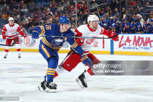 Rasmus Dahlin of the Buffalo Sabres and Christian Fischer of the Detroit Red Wings skate after the puck during an NHL game on December 5, 2023 at...