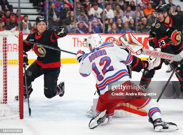 Jakob Chychrun of the Ottawa Senators keeps the puck out of the net of Anton Forsberg after a shot from Nick Bonino of the New York Rangers as Travis...