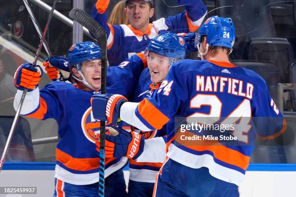 Mike Reilly of the New York Islanders is congratulated by Simon Holmstrom and Scott Mayfield after scoring a goal against the San Jose Sharks during...