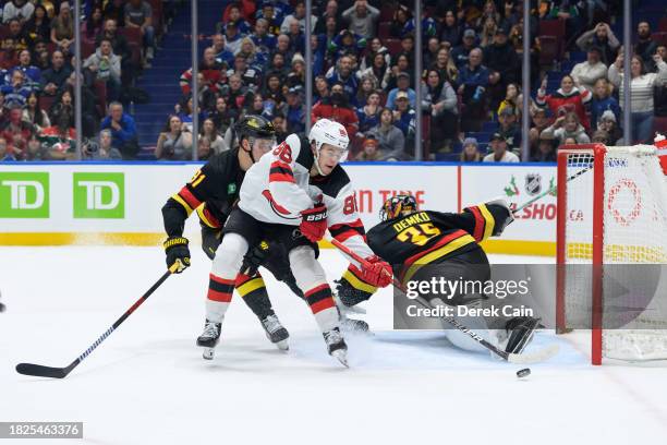 Nikita Zadorov and Thatcher Demko of the Vancouver Canucks defend Jack Hughes of the New Jersey Devils during the third period of their NHL game at...