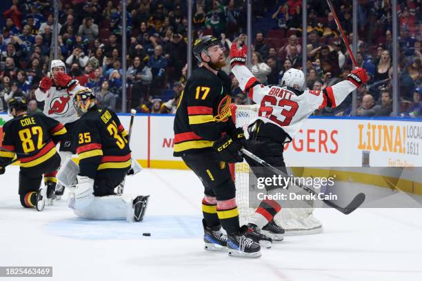 Jesper Bratt of the New Jersey Devils celebrates after scoring the game-winning goal against Thatcher Demko as Filip Hronek of the Vancouver Canucks...