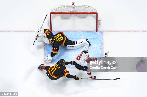 Nikita Zadorov and Thatcher Demko of the Vancouver Canucks defend Jack Hughes of the New Jersey Devils during the third period of their NHL game at...