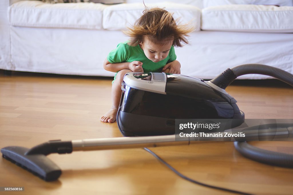 Small boy having fun with a vacuum cleaner