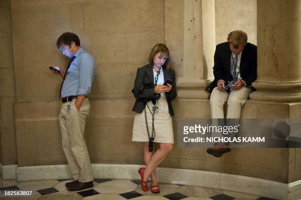 Reporters check their smartphones while waiting outside US House Speaker John Boehner's office at the US Capitol in Washington on September 30, 2013...