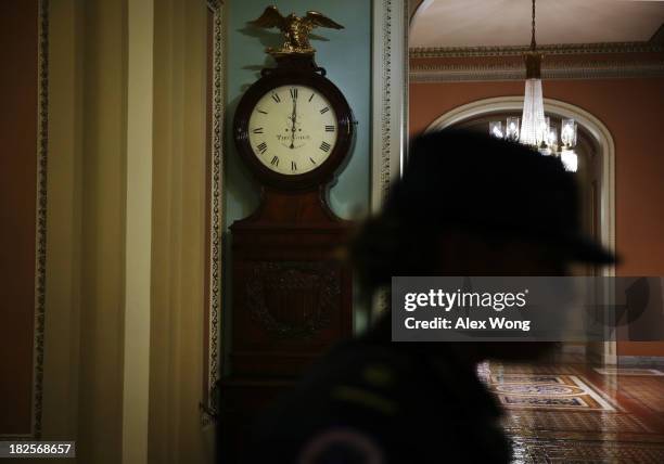 Capitol Hill Police officer passes by the Ohio Clock which shows the time has just passed midnight on the Senate side of the U.S. Capitol October 1,...