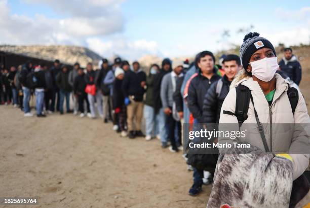 Asylum seeking migrants stand at a makeshift camp along the U.S.-Mexico border as they await processing by the U.S. Border Patrol on December 1, 2023...