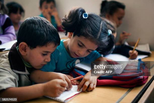 Syrian children attend a class at a school in the Masai Hanano district in the northern Syrian city of Aleppo on September 23, 2013. "The reopening...