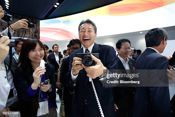 Kazuo Hirai, chief executive officer of Sony Corp., laughs as he tries out a Sony Xperia Z1 smartphone with the Sony DSC-QX100 smartphone attachable...