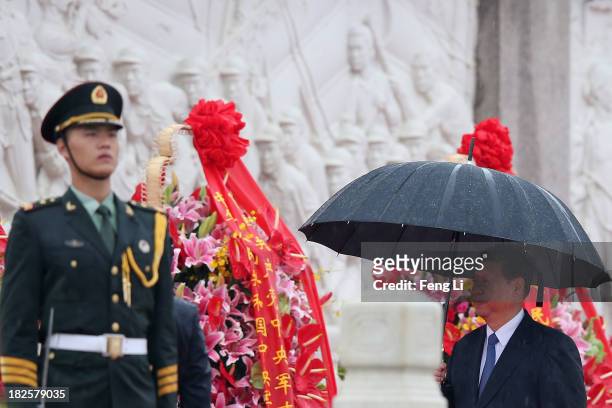 Chinese President Xi Jinping walks past the Monument to the People's Heroes while holding umbrellas during a ceremony marking the 64th anniversary of...