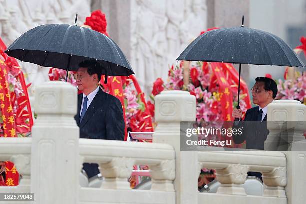 Chinese President Xi Jinping and Premier Li Keqiang walk past the Monument to the People's Heroes while holding umbrellas during a ceremony marking...