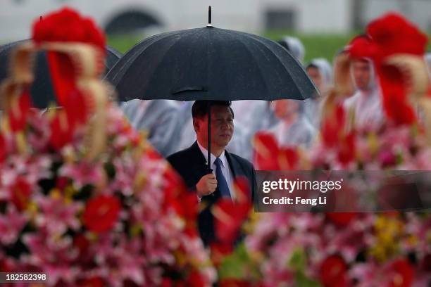 China's President Xi Jinping hold umbrella as he arrive for a tribute ceremony marking the 64th anniversary of the founding of the People's Republic...