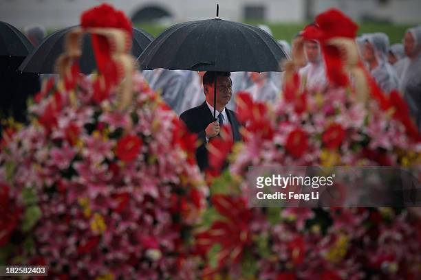 China's President Xi Jinping hold umbrella as he arrive for a tribute ceremony marking the 64th anniversary of the founding of the People's Republic...