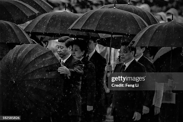 Chinese President Xi Jinping opens his umbrella as Premier Li Keqiang and Chinese Communist Party top leaders stand with umbrellas in the rain after...